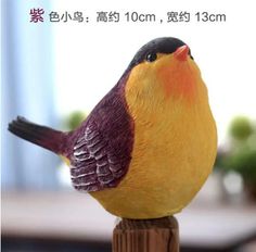 a yellow and red bird sitting on top of a wooden post next to a table