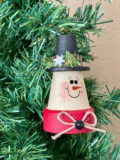 a christmas ornament hanging from a tree with snowman on it's head