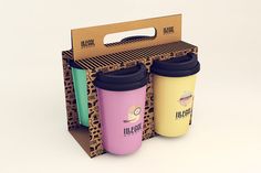 three different colored coffee cups in a cardboard box