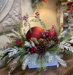 a christmas centerpiece with pine cones, berries and greenery on a wooden table