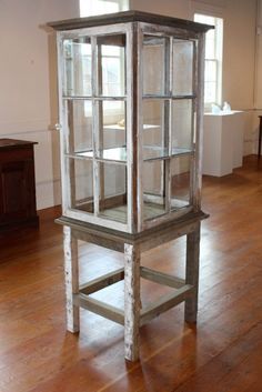 an old wooden display case in the middle of a room with wood floors and white walls