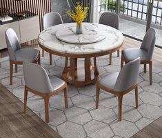 a dining room table with grey chairs and a white marble topped centerpiece in the middle