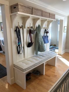 a white bench with several coats hanging on it's hooks and two purses