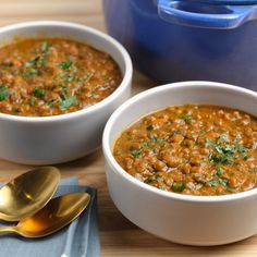 two bowls of soup with spoons on a table