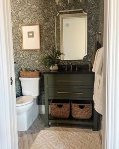 a bathroom with black and white wallpaper, green vanity sink and basket baskets on the floor