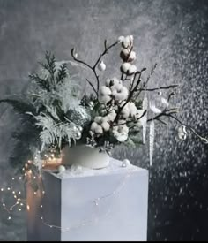 a vase filled with white flowers and greenery on top of a block of ice