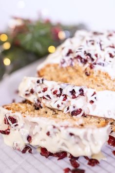 two slices of cake with cranberry toppings on a cooling rack next to a christmas tree