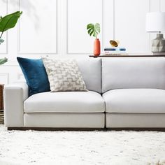 a white couch with blue and green pillows on top of it in a living room