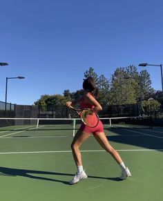 a woman in pink is playing tennis on a green court with white and black lines