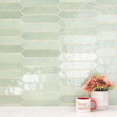 a vase filled with flowers sitting next to a mug on top of a white counter