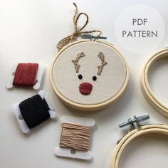 three different types of embroidery on wooden hoops with scissors and thread spools