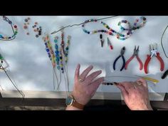 a woman is making beaded bracelets with scissors and beads on the wall behind her