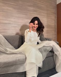 a woman sitting on top of a gray couch