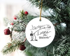 a white ornament hanging from a christmas tree with writing on the front and back