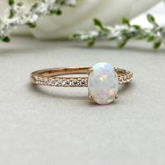 a white opal and diamond ring sitting on top of a table