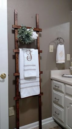 a bathroom with a ladder holding towels on the wall and a potted plant sitting on top of it