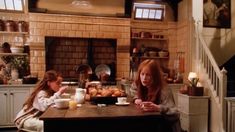 two women sitting at a table in a kitchen