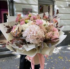 a person holding a bouquet of flowers in front of a building