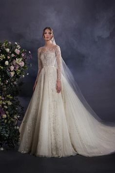 a woman in a wedding dress standing next to a flower bush and wearing a veil