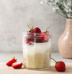 a jar filled with food sitting on top of a wooden table next to strawberries