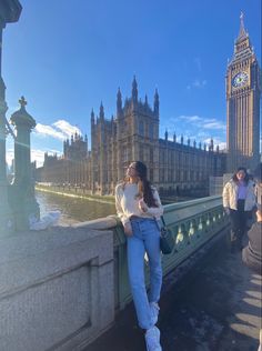 a woman standing on the side of a bridge next to a clock tower