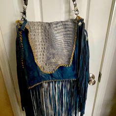 a handbag hanging on a door handle in front of a white door with blue fringes