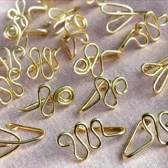 many different types of metal wire on a white table cloth with pink fabric in the background