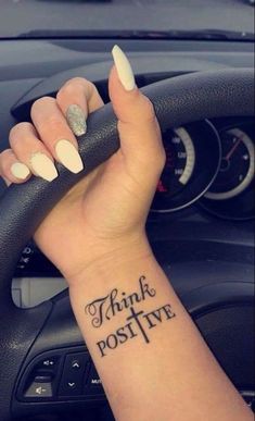 a woman's wrist with the words think positive tattooed on her left arm and an arrow