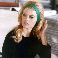 a woman with long blonde hair wearing a green headband and looking at the camera