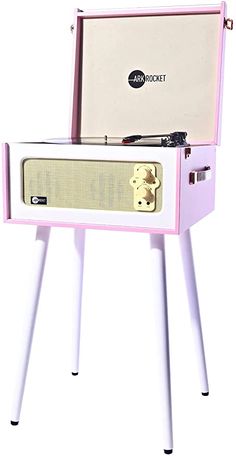 a pink and white record player sitting on top of a table with legs in front of it