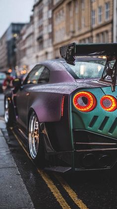 the rear end of a sports car with its lights on