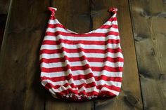 a red and white striped bag sitting on top of a wooden floor next to a wall