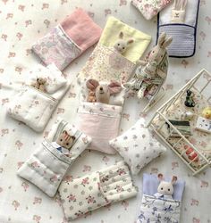 several small stuffed animals and blankets on a bed with floral print sheets in the background