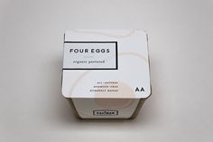 an open carton of four eggs on a white surface with a black and white label