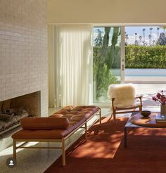 a living room filled with furniture and a fire place in front of a large window