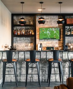 a bar with three stools in front of it and a television on the wall