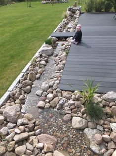 a man sitting on the roof of a house next to a river running through it