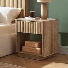 a nightstand with a lamp on it next to a bed