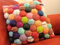 a multicolored pillow sitting on top of an orange couch