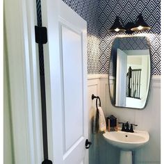 a white sink sitting under a bathroom mirror next to a wall mounted faucet