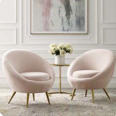 two pink chairs sitting next to each other in front of a painting