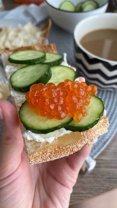 someone is holding up a sandwich with cucumber and red cavia on it