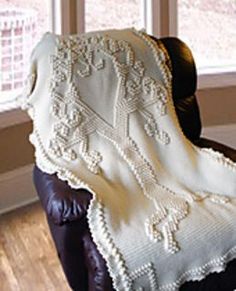 a white blanket sitting on top of a leather chair