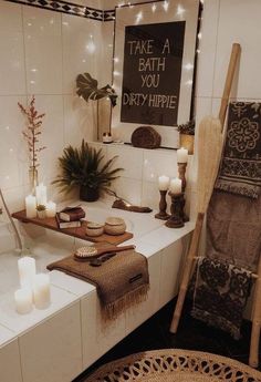 a bath room with candles and towels on the counter next to a mirror that says take a bath you dirty hippie