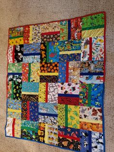 a colorful quilt is hanging on the wall next to a carpeted floor and rug