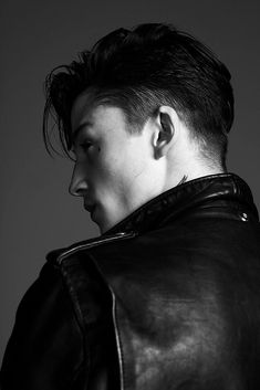 black and white photograph of a man wearing a leather jacket with ear piercings on his ears