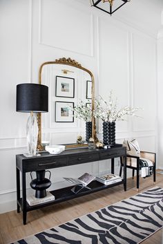 a black table with a mirror and vases on it next to a zebra rug