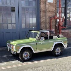 an old pick up truck is parked in front of a brick building with large windows