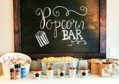 a chalkboard with popcorn bar written on it next to other snacks and condiments