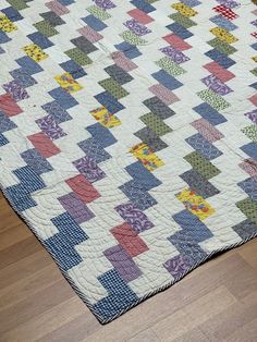 an old quilt is laying on the floor in front of a wood flooring area